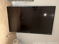 Front view of Sharp Aquos TV leaning against wall, showing screen and bezel