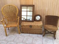 Front view showing two wicker chairs, large wicker chest, wooden framed mirror, and round wall clock against wood paneled wall.