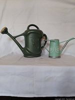 Full view of both watering cans side by side showing size and color differences