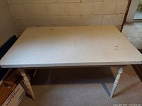 Rectangular formica tabletop with light-colored turned wooden legs, showing stains and discoloration.