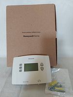 Honeywell Home thermostat front with box and mounting screws.