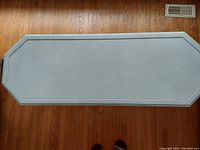Top view of rectangular white painted wood coffee table with chamfered corners and black line detail near edges.
