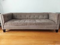 Gray Structube Loretta sofa with tufted cushions from front view on wood floor