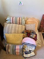 Full view of assorted accent pillows and throw blanket stacked together