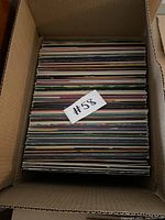 Photo of a full cardboard box filled with vinyl records set vertically and tightly packed.