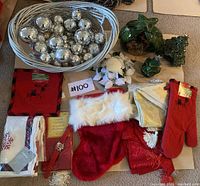 Overview of the Christmas decoration lot showing silver ornaments in basket, stockings, mitt, table runners, floral decor, and small trees.