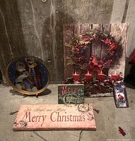 Photo showing multiple Christmas-themed decorative items including a nativity plate, vintage Christmas signs, cardinal bird plaque, and fall wreath art canvas.
