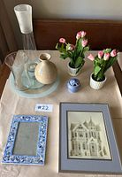 Photo of 3 vases, 2 pots of artificial pink tulips, small ceramic jar, light blue Lazy Susan, mosaic picture frame, and framed Debbie Patrick 3D art print.