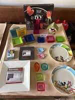 Wide view photo of the entire lot including plates, candle holders, colorful appetizer plates, glass platter box, and small ceramic dishes.