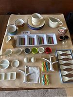 Full lot on brown background with variety of hors d'oeuvres and party servingware including plates, spoons, cups, pitchers, racks, and clip holders.