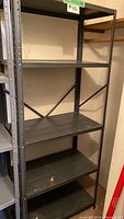 Full view of black metal shelving unit with five shelves, showing structure and condition.