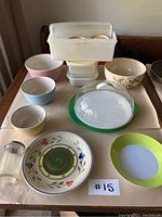 Overview of various pastel ceramic bowls, floral bowl, Tupperware containers stacked and assorted colorful plates and serving pieces