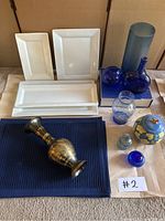 Full overview of all items including placemats, white ceramic serving platters, blue glass vases, and metallic decorative vase.