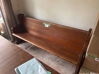 Side angle of solid wood church pew showing seat, backrest, armrest, and wood grain finish.