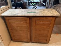 Front view of the wooden storage island with stone top showing paneled doors.