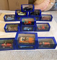 Ten boxed diecast Tintin cars arranged in pyramid formation on carpeted floor