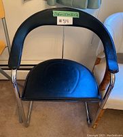 Front view of vintage black vinyl and chrome chair showing padded seat and curved backrest with chrome frame.