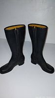 Pair of vintage black leather boots standing upright on white surface, showing front and side views.