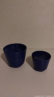 Two blue mid-century modern ceramic planter pots, showing their full front view with textured Fat Lava glaze.