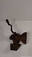 Side view of antique coffee grinder showing hand crank and mounting bracket