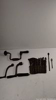 Full lot showing five handle pieces, drill bits in a cloth holder, and two stove handles.
