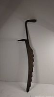 Front view of antique sickle showing notched blade, curved handle, and wooden grip