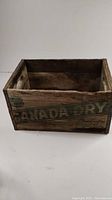 Wooden crate with clear but worn Canada Dry logo and text on one side.