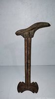 Full view of antique metal cobbler shoe stand showing its foot-shaped top and vertical stem