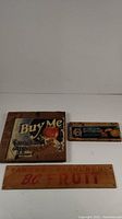 Front view of three wooden fruit box end boards with vintage advertising labels, showing size differences and peeled paint