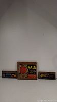 Three wooden fruit crate end boards with original colorful advertising labels arranged on a flat surface.