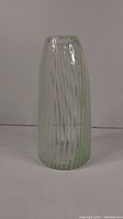 Tall clear-to-light-green Murano glass vase with vertical white swirl line pattern, front view on plain background.