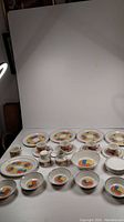 Full view of all dinnerware items laid out on table showing variety of plates, cups, saucers, bowls, creamer and sugar bowl.
