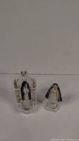 Full view of both porcelain Mary statues, one in shrine holding baby Jesus, other wearing blue shawl