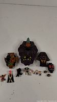 Full shot showing multiple Mighty Max skull-shaped playset cases and several small figures arranged in front.