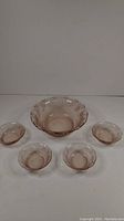 Full set view showing one large pink salad bowl and four matching smaller side bowls embossed with grapes