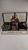 Overview photo showing the tailor's sample display case with fabric swatches neatly arranged and promotional print inside lid.