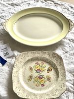 Oval pale yellow plate with handles and simple double-line border.