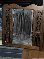 Vintage mirror with dark wood frame displaying detailed carved side panels and spindles, scalloped top edge, rectangular mirror glass.