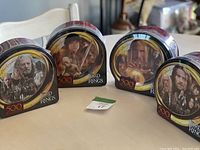 Four new, sealed Lord of the Rings puzzles in metal tins, each showing distinct character artwork from the series on the front.
