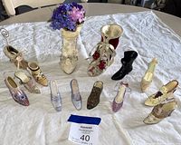Wide shot showcasing all 11 miniature shoes and boots arranged on a white cloth with floral Victorian-style boots standing upright.
