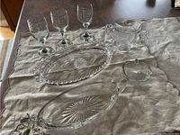 Photo showing the entire set of six crystal glassware pieces on a cloth background: four wine glasses, an oval dish with bead edge, a long oval etched dish, a small bowl with handles, and a pedestal dish.
