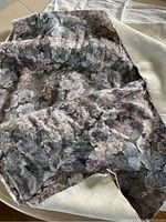 Close-up of large floral patterned upholstery fabric in gray, purple, and pink tones.