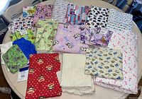 Photo of folded and stacked colorful fabric with cartoon and animal prints on a table