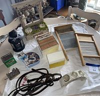 Photo showing the Betty Crocker recipe box with index cards, two wooden washboards, coiled leather horse reins, black metal lantern, metal tin boxes, decorative cat tin, and a ceramic candle holder with glass containers.