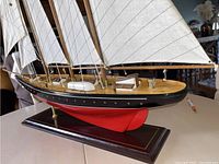 Front view of the decorative sail boat model showing detailed sails, deck, and hull on wooden base.