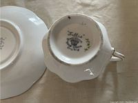 Bottom of teacup showing Frellis Fine China England markings with handwritten markings and some wear on rim base