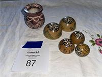 Photo showing the full set including the clay pot and five nesting balls placed on a cloth beside the auction tag.