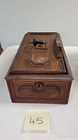Rectangular wooden antique box with keyhole on front and knob on top panel, showing the box with the cover detached and placed behind.