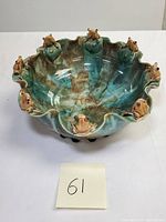 Top front view of the ceramic bowl showing the glaze colors and nine frogs on the scalloped edge.