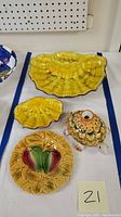 A set of four vintage ceramic items: two yellow oyster shell bowls/dishes, a turtle shaped ceramic vessel with floral decoration, and a round decorative plate with floral motif.